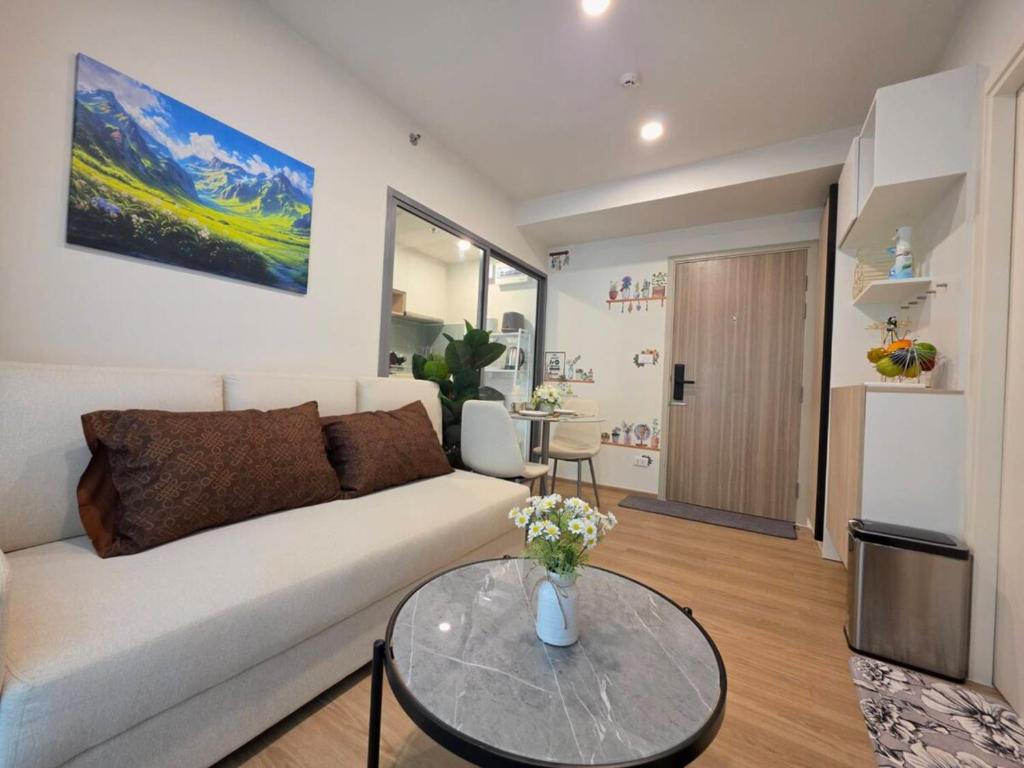 a living room with a white couch and a glass table at Phyll Condo Room in Wichit in Ban Rangeng