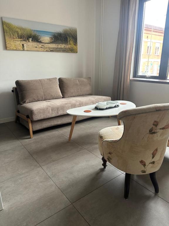 a living room with a couch and a table and a chair at Mysig lägenhet Malmö Centralt in Malmö