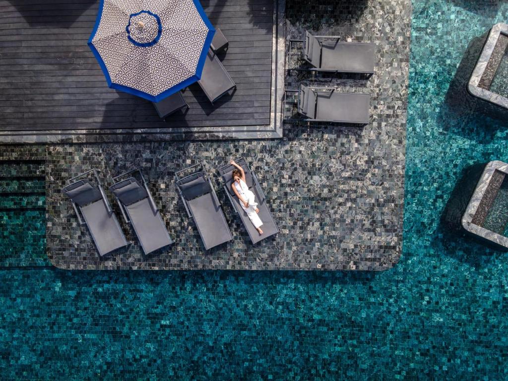 an overhead view of a woman standing next to chairs and an umbrella at Hotel Indigo Phuket Patong by IHG in Patong Beach