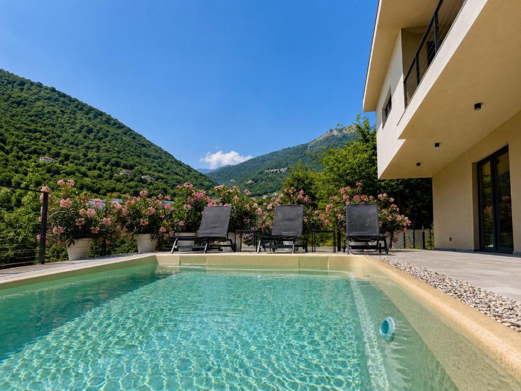 a swimming pool in front of a house with a mountain at Villa Perla di Draga in Mošćenička Draga