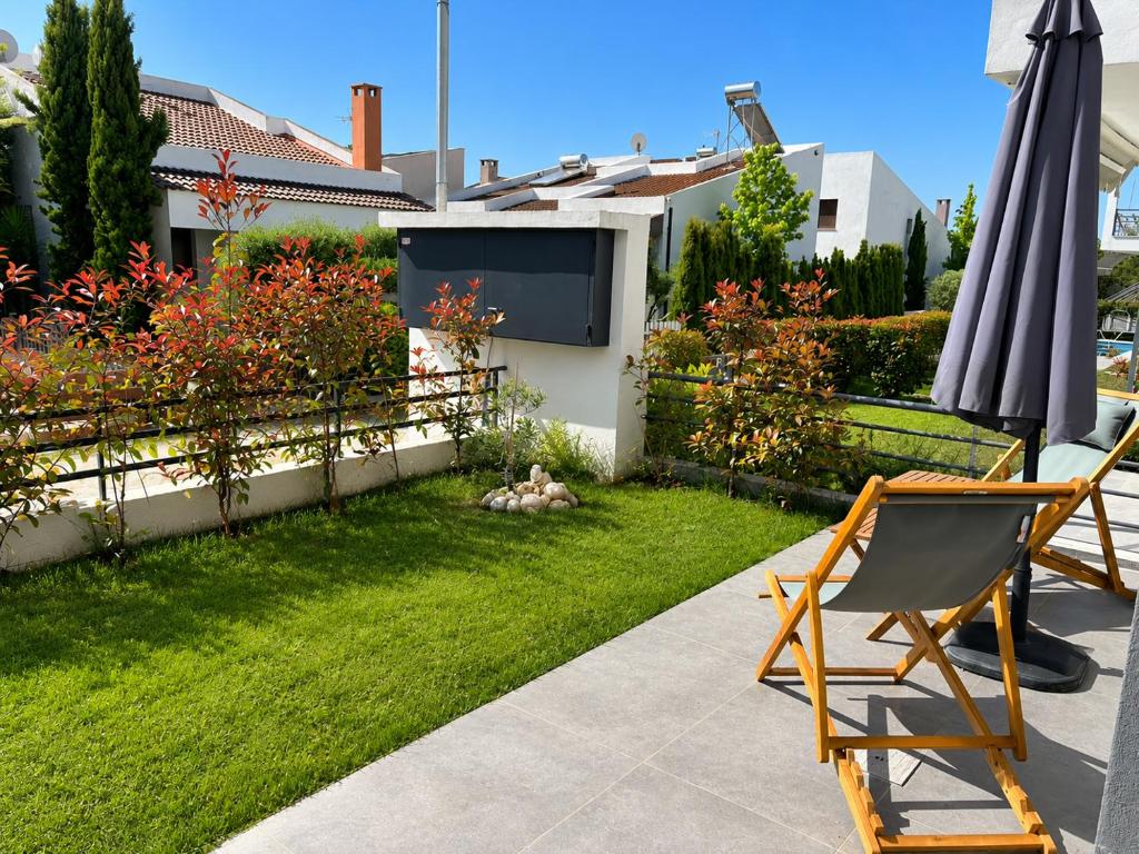 a patio with two chairs and an umbrella in a yard at Aelia Blu 1 in Ofrínion