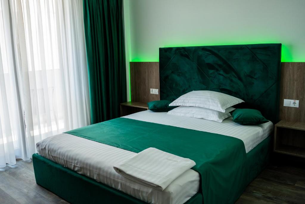 a bedroom with a large bed with green and white pillows at Wezen in Vama Veche