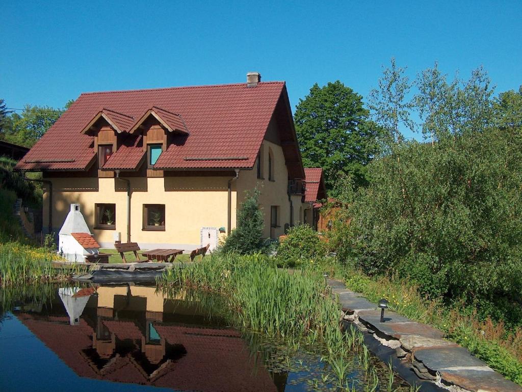 a house with a red roof next to a river at Spacious holiday home in Przesieka with sauna in Przesieka