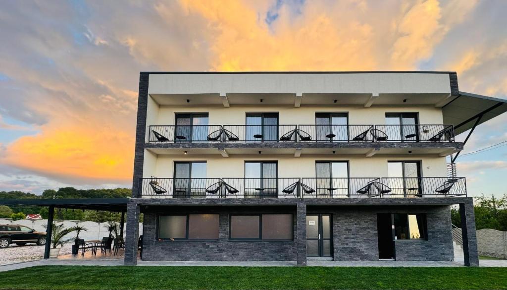 a building with balconies and a sunset in the background at Cataleya House in Oeşti-Pămînteni