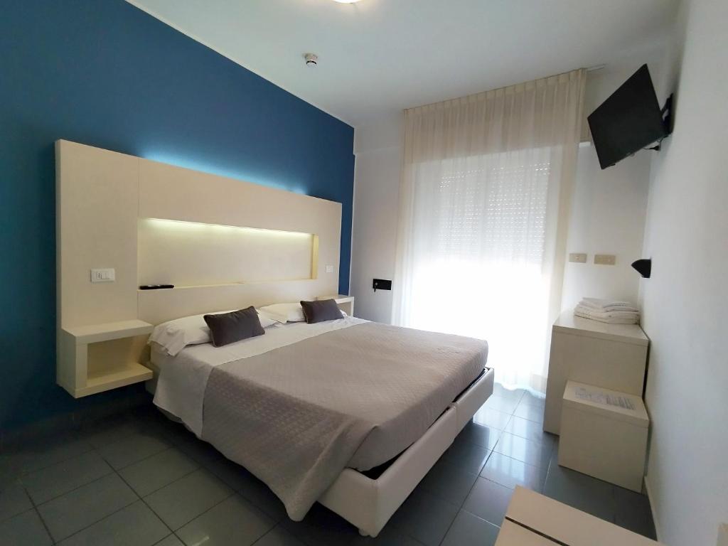 a bedroom with a large bed and a blue wall at Hotel Desire' in Riccione