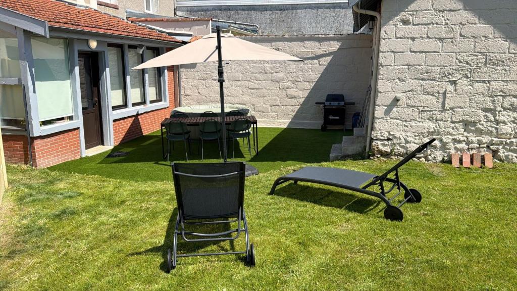 a picnic table and an umbrella in a yard at Maison Cosy, proche Reims, La Nichée in Bazancourt