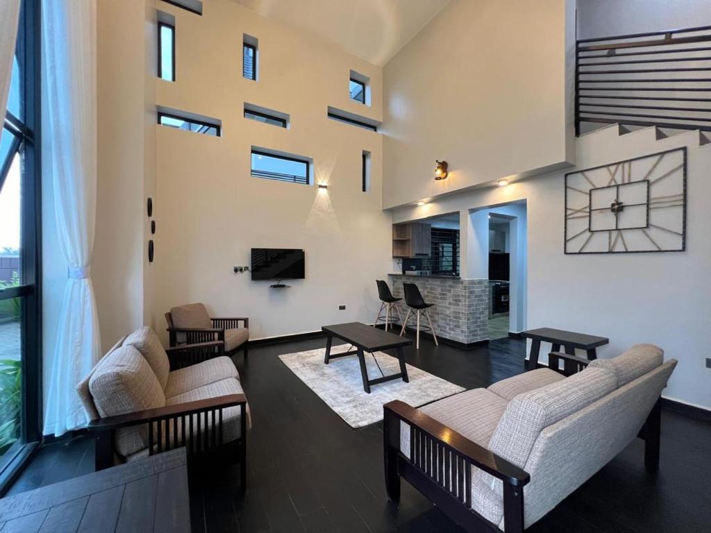 a living room with couches and tables and a large window at DLK Living in Kampala