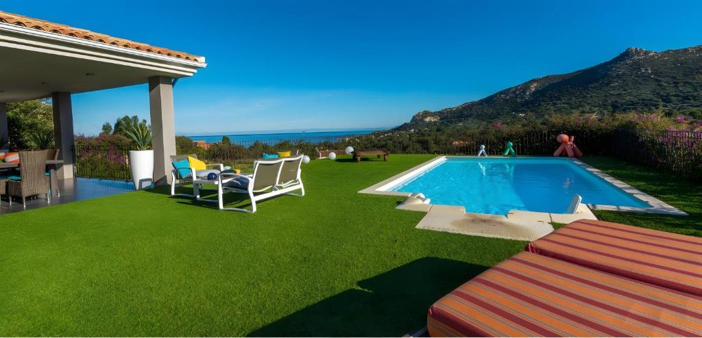 a backyard with a swimming pool and green grass at Villa Mare Monti in Lumio