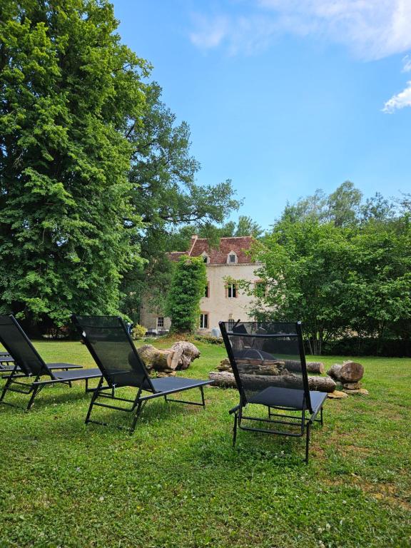 three chairs sitting in the grass in front of a house at La Tuilerie Du Cinéaste in Courlon