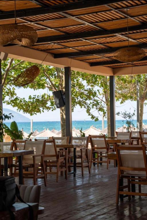 a restaurant with tables and chairs and a view of the ocean at Oasis Apart-Hotel Residence Vlore in Vlorë