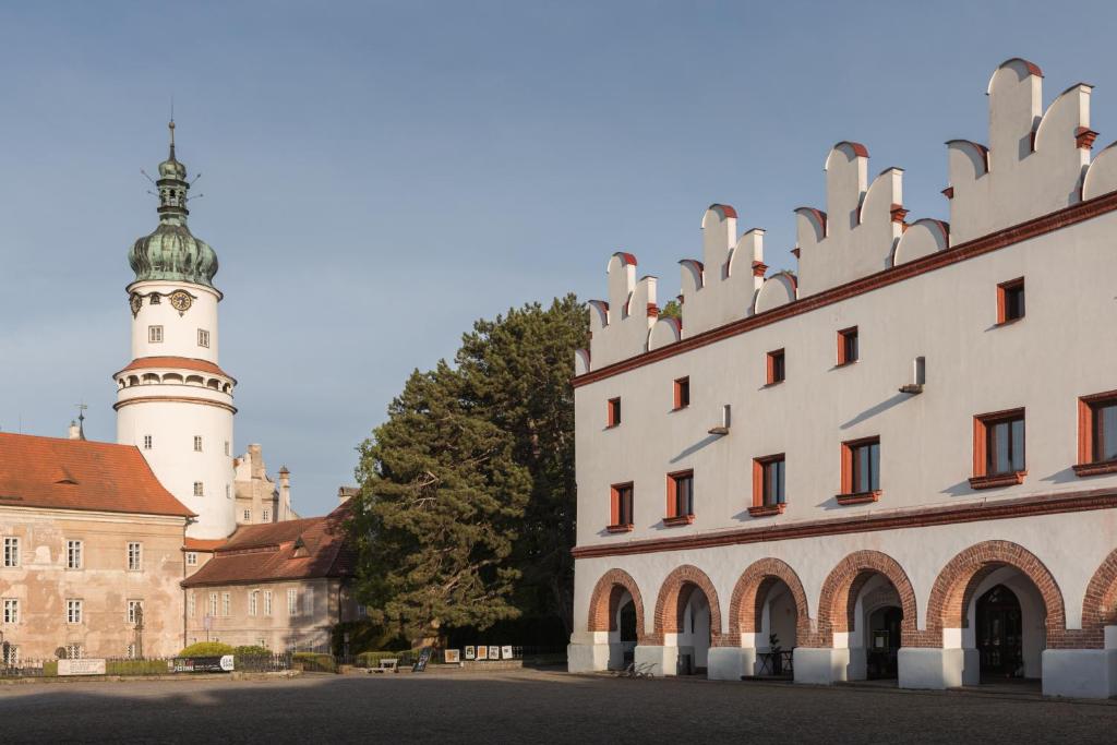 a building with a clock tower next to a castle at Vlaštovčí dům in Nové Město nad Metují
