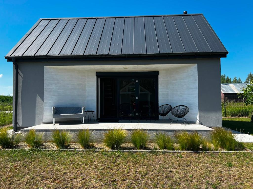 a black and white building with a couch and chairs at Domek Za Wyspą 1 in Chmielów