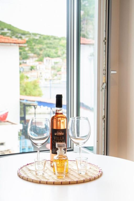 a bottle of whiskey and two wine glasses on a tray at Gaia Trikeri Suites in Ayía Kiriakí