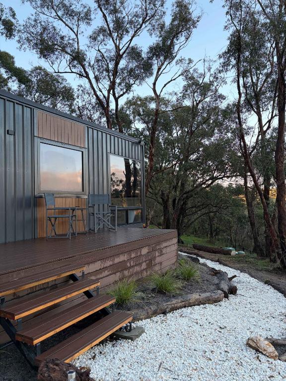 ein kleines Haus mit einer Terrasse und einem Tisch in der Unterkunft Zenith Tiny Home in Montacute