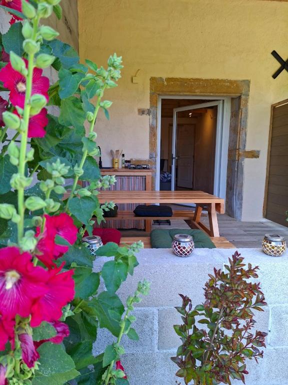 a patio with a wooden bench and red flowers at Estefana in Chambilly