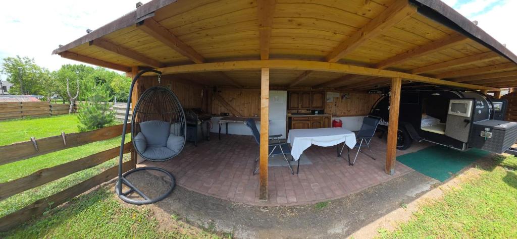 a gazebo with a table and chairs under a roof at Gästehaus Kathi Campingplatz Buschcamper in Gyenesdiás