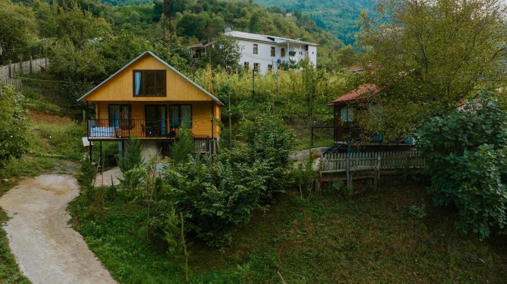 a small yellow house on the side of a hill at River Land Cottages in Tsʼkhmorisi