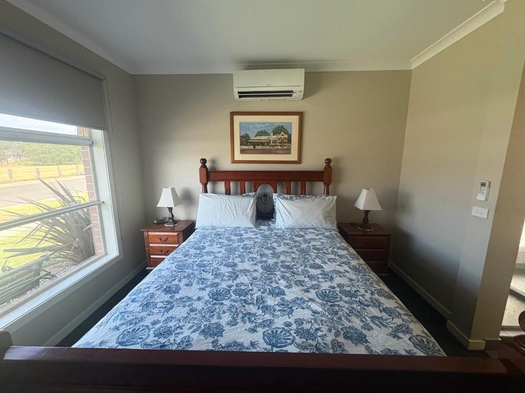a bedroom with a bed with a blue and white comforter at Park Views Guest Room in Kilmore