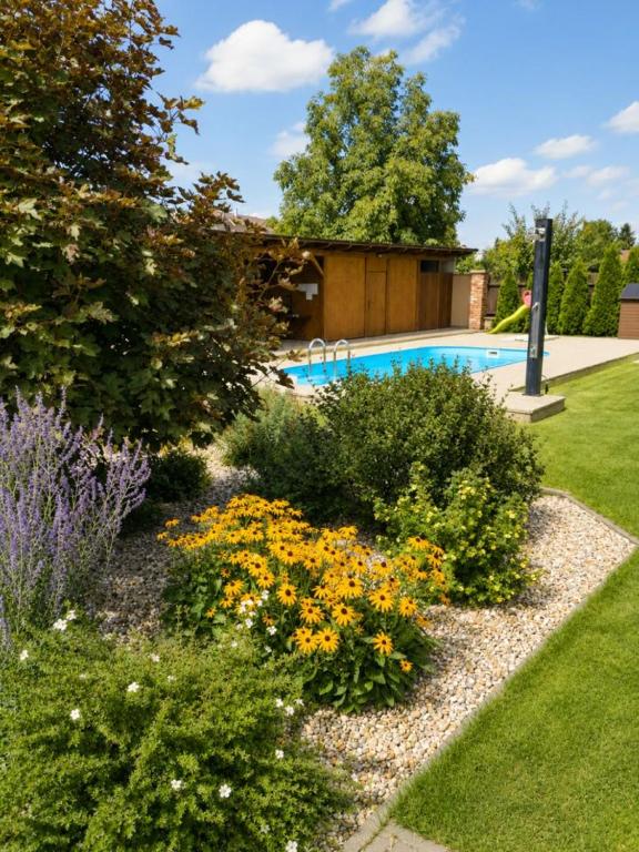 a garden with flowers and a swimming pool at Penzion U Kyjovky, Týnec in Týnec