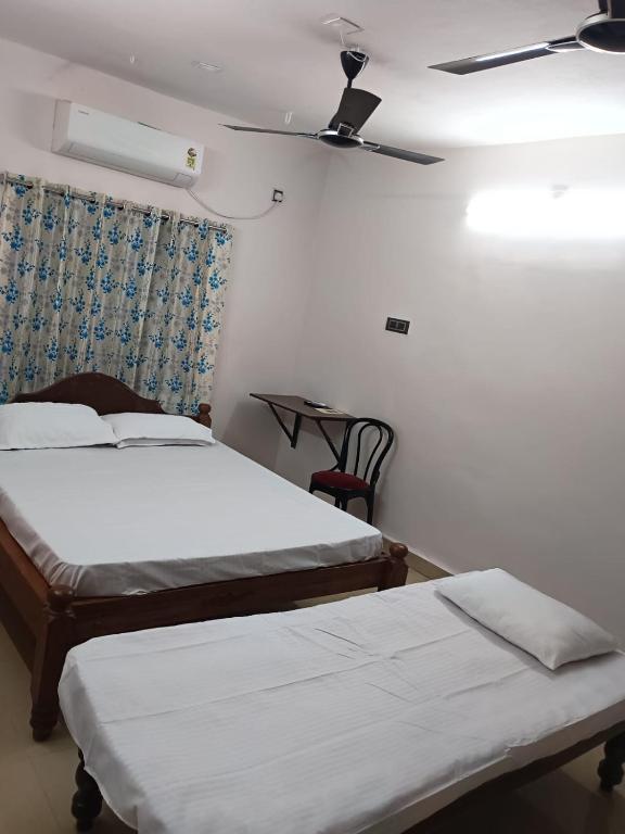a bedroom with two beds and a ceiling fan at Saimithra Riverview Homestay in Tirunelveli