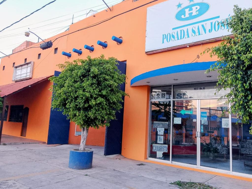 an orange building with a tree in front of it at Posada San José, Hotel in Puebla