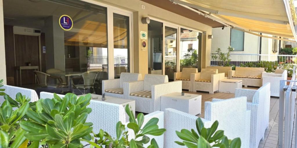 a patio with white chairs and tables and plants at Hotel Atlas in Gabicce Mare