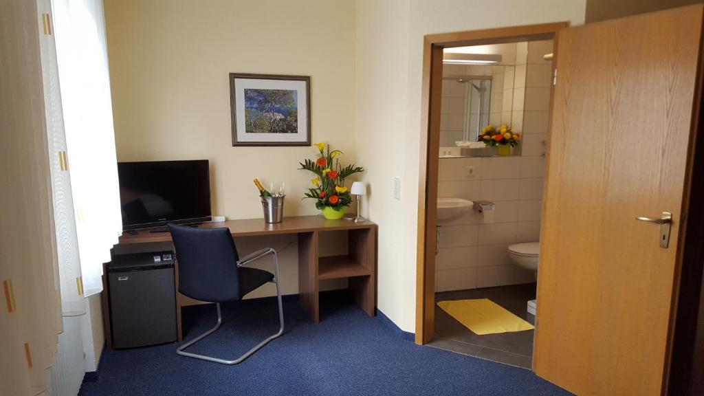 a room with a desk with a computer and a bathroom at Hotel Garni WEISSES LAMM in Erlangen
