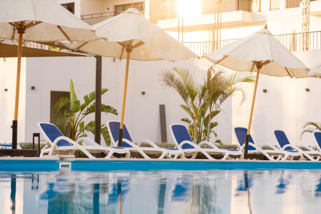 a swimming pool with lounge chairs and umbrellas at Settle inn Jebal apartments in Cairo