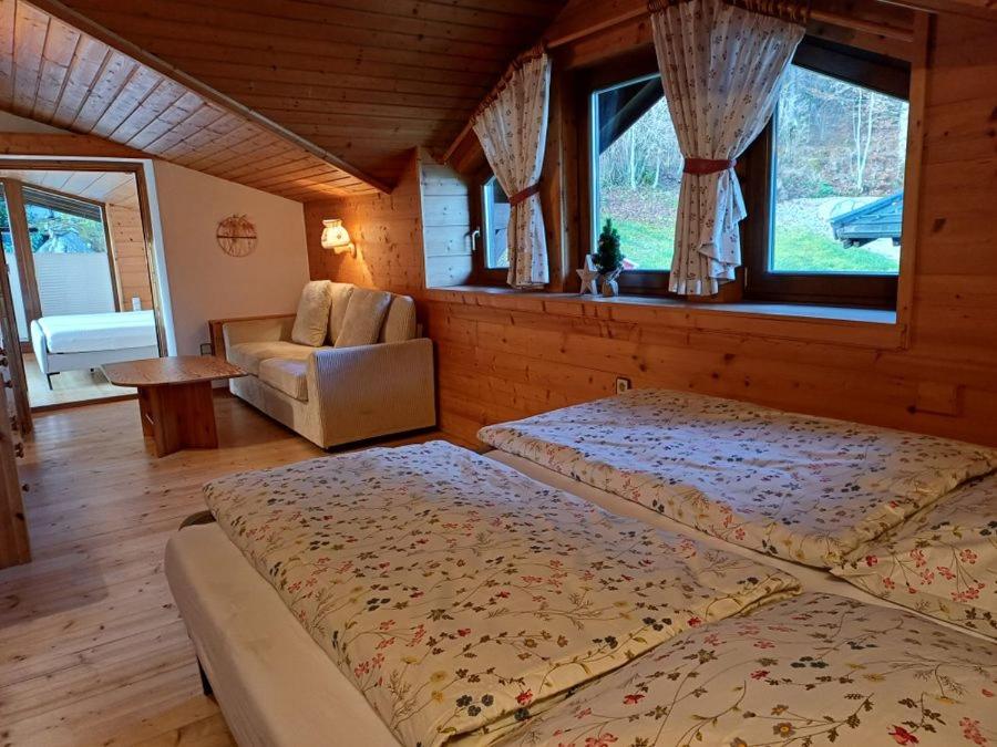 a bedroom with two beds and a chair and windows at Rauchenberg Apartments in Lofer