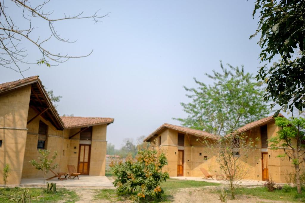 a row of houses with trees in the foreground at Tiger Track Eco Lodge in Bardiyā
