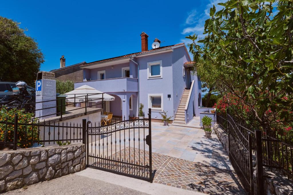 a white house with a fence in front of it at Apartmani Raić in Mali Lošinj