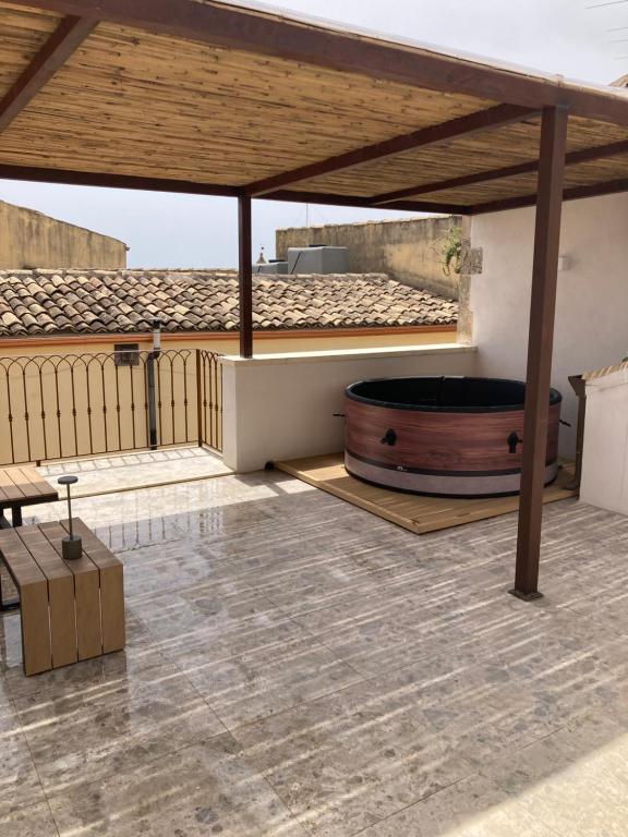 a patio with a hot tub and a wooden roof at Casa Fioraliso in Noto