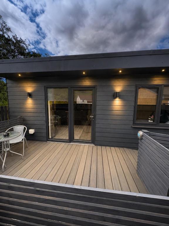 a house with a wooden deck with a table on it at Hillview Cabin in Oban