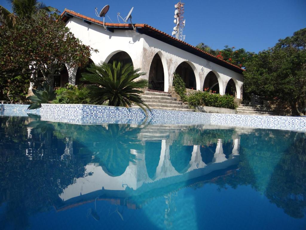 uma piscina com um edifício ao fundo em Casa Dos Arcos Bed and Breakfast em Arraial do Cabo