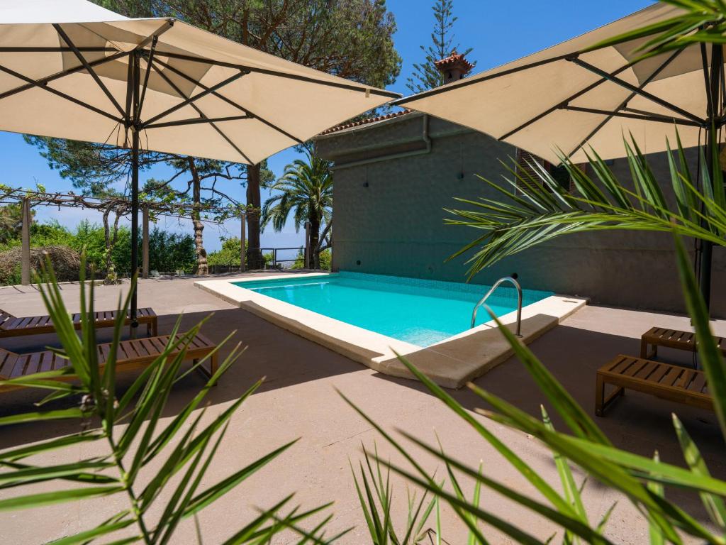 a swimming pool with two umbrellas and two chairs at Finca Fuente Laurel in Arucas