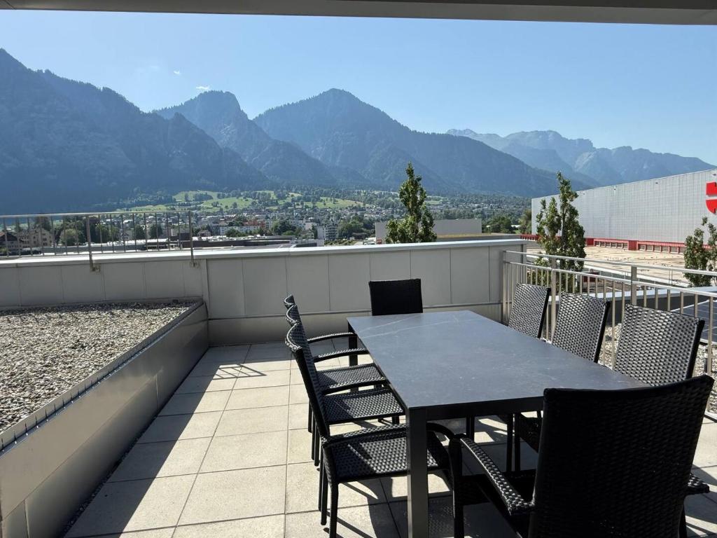 a table and chairs on a balcony with mountains at Penthouse mit Panoramaterrasse & Bergblick in Landquart in Landquart