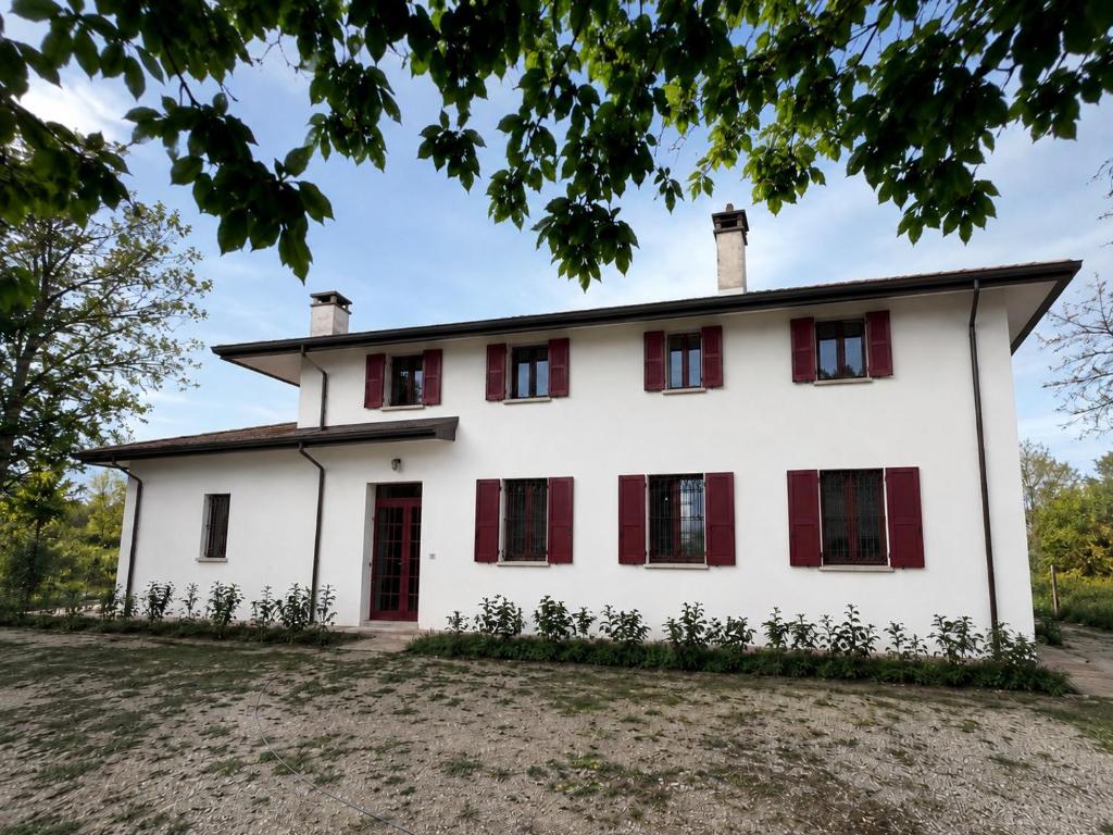 an old white house with red shutters at B&B La Vigna dei Fratelli in lido degli scacchi