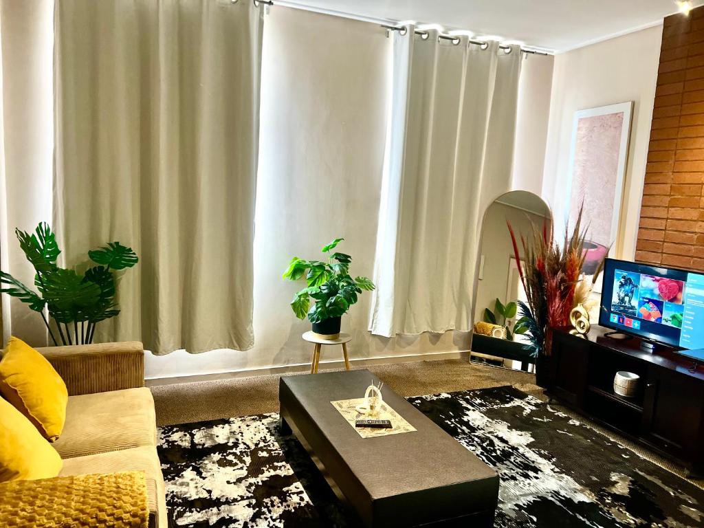 a living room with a couch and a tv at Warm & Cozy Diamonds Hotel in Johannesburg