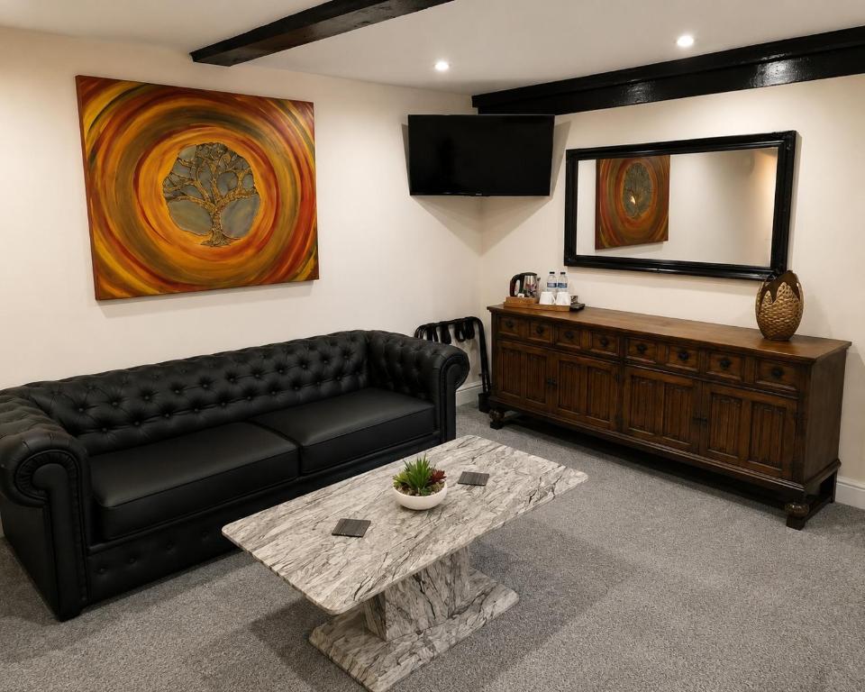 a living room with a black leather couch and a mirror at The George and Dragon Inn in Long Melford