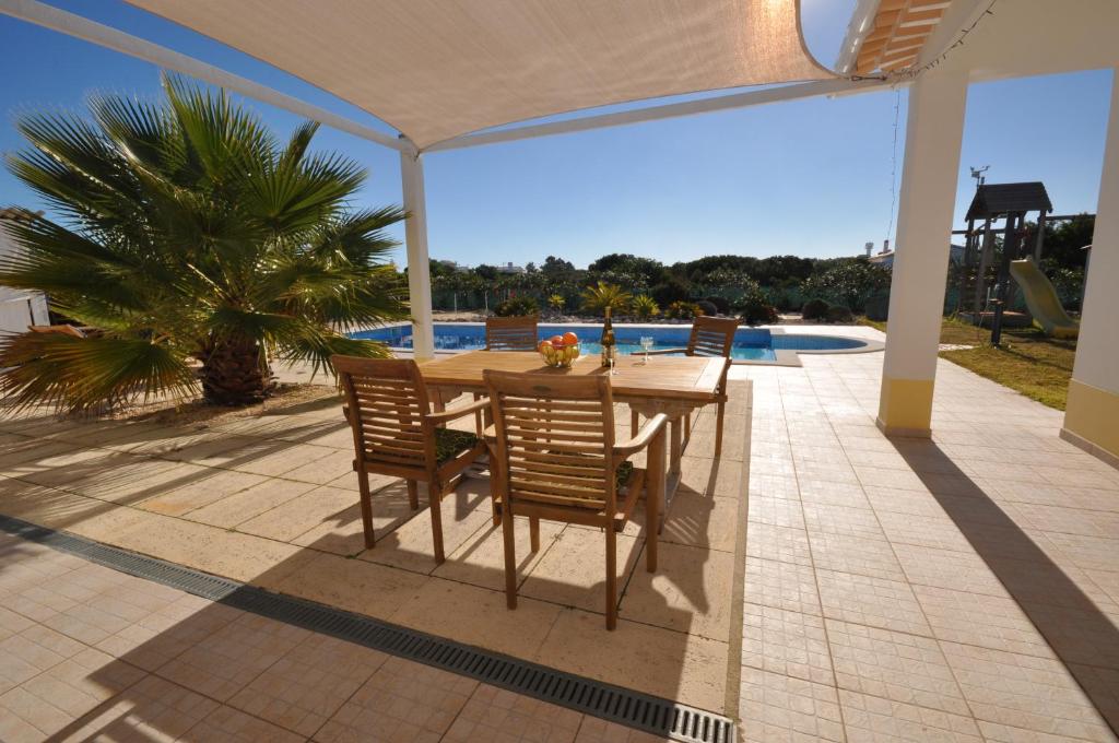 a patio with a table and chairs and a palm tree at Casa Sol in Aljezur