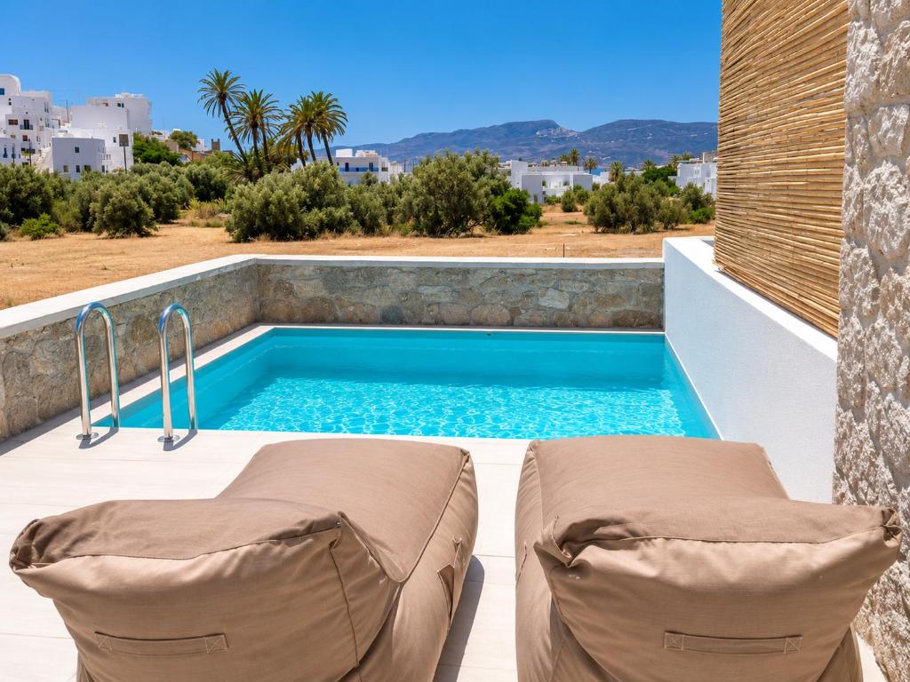 a swimming pool on a patio with two lounge chairs next to it at Milea amare Suites in Adamantas