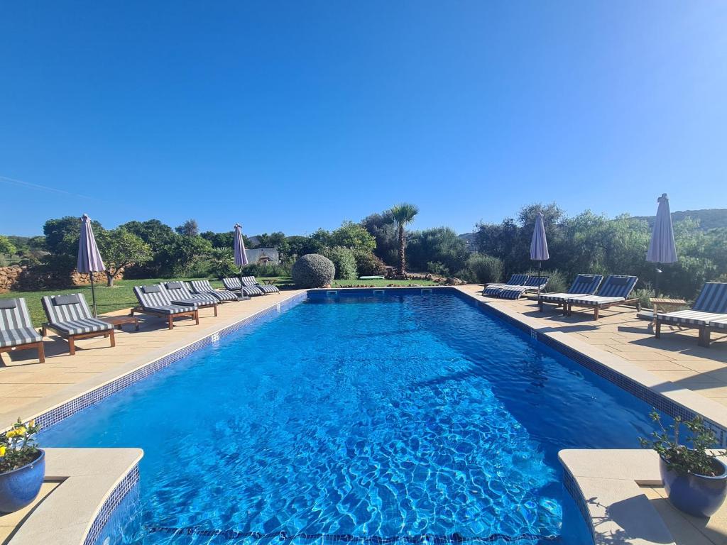 a swimming pool with chaises and chairs around it at Quinta da Luz - A Luxury Boutique B&B in Silves