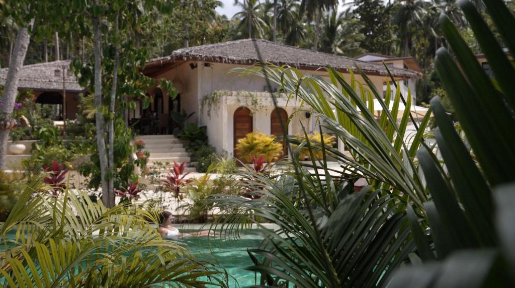 a house with a swimming pool in a garden at Arcana Wellness Center - Adults Only in Ko Phangan