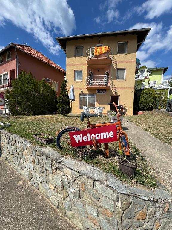 a bicycle parked next to a stone wall with a welcome sign at Deskom Žuta Vila in Veliko Gradište