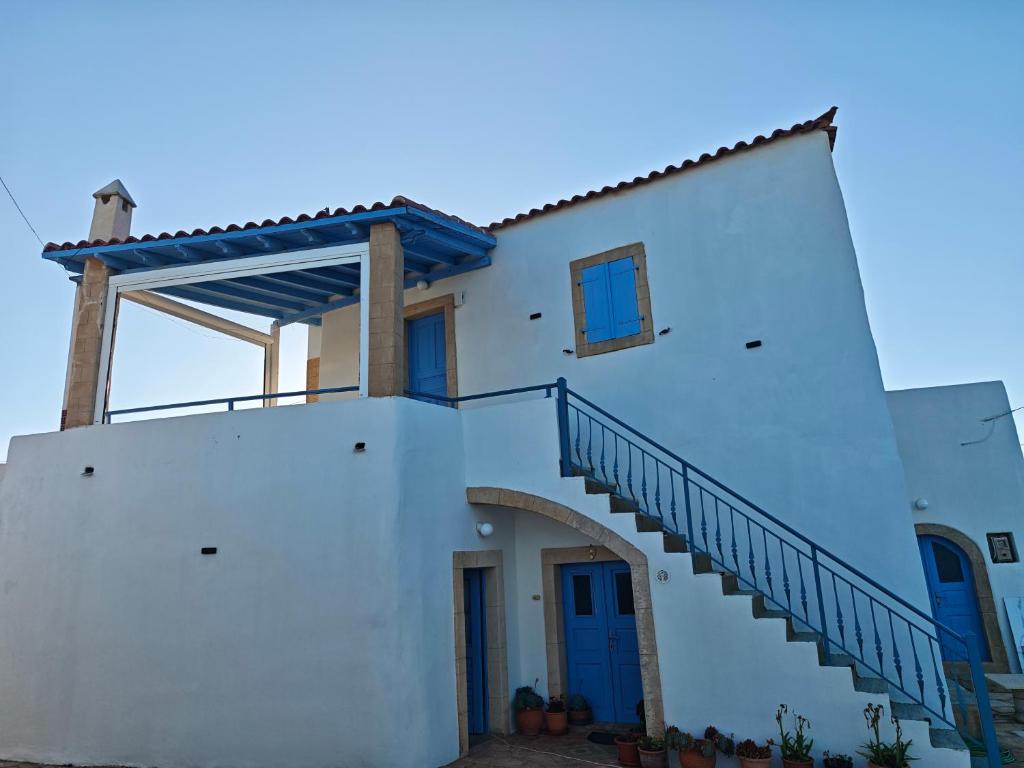 a white house with a blue door and stairs at Kastri in Kythira