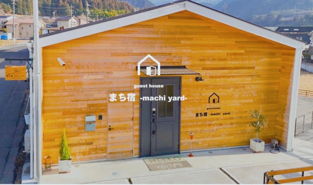 ein Holzgebäude mit einer Tür in der Unterkunft まち宿-machi yard- in Nakatsugawa