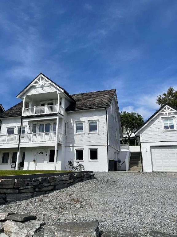 a large white house with a garage at Bright & Spacious Apartment by the Sea, Free Parking, 10min to Airport, 12min to Ålesund in Ytterland
