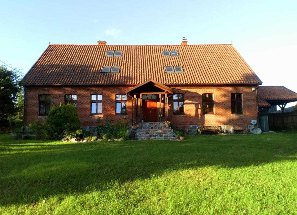 a brick house with a red roof on a lawn at Agroturystyka Czułe Miejsce in Zdory