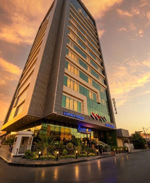 a tall building with a sunset in the background at Blue Moon Hotel in Erbil
