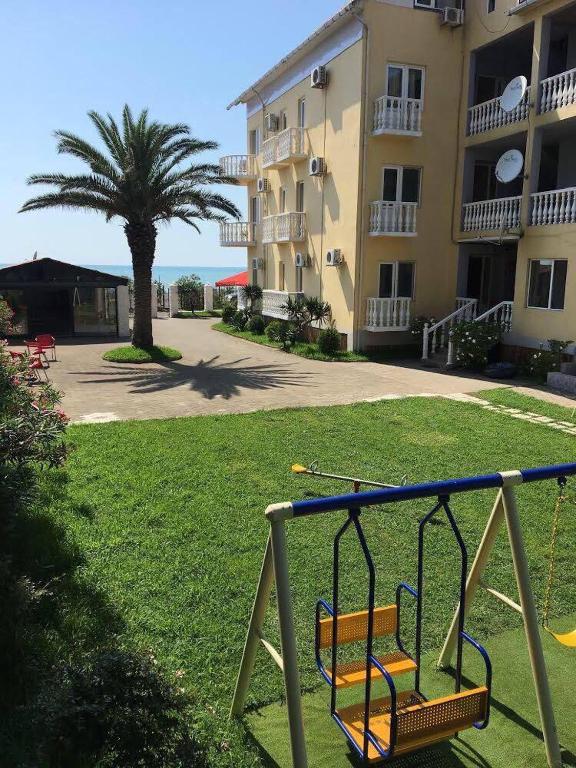 a swing in front of a building with a palm tree at Квартира in Ureki